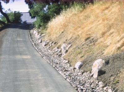 Rock lined roadway drainage swale, with large rock